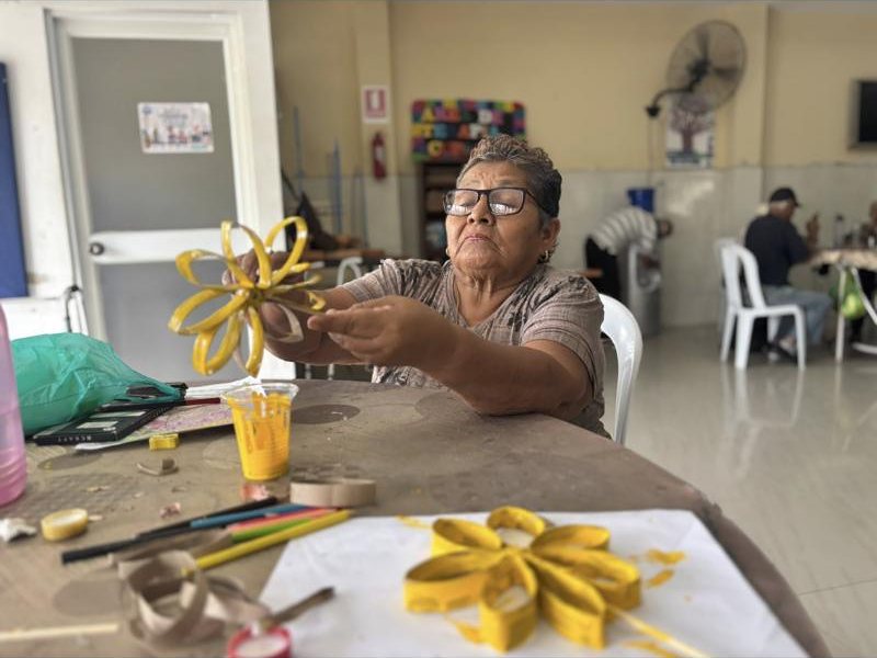 Una adulta mayor muestra su flor de papel