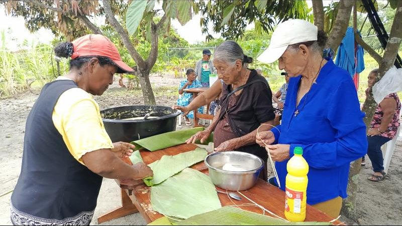 Adultas mayores preparan tamales en hojas de plátano